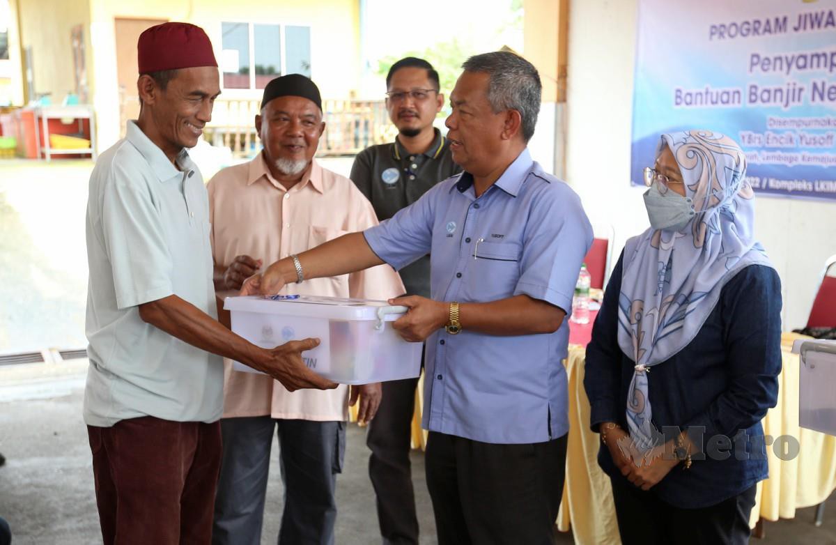 YUSOFF (dua kanan) diiringi Pengarah LKIM Kelantan, Khuzaimah Hussin menyampaikan sumbangan barangan keperluan asas dan wang tunai nelayan yang terjejas akibat banjir di Tumpat. FOTO Nik Abdullah Nik Omar