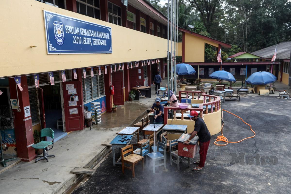 KAKITANGAN sekolah membersihkan peralatan meja dan kerusi selepas dilanda banjir sebagai persediaan pembukaan sekolah yang bermula esok, 1 Januari 2023 di SK Kampung La. FOTO Ghazali Kori