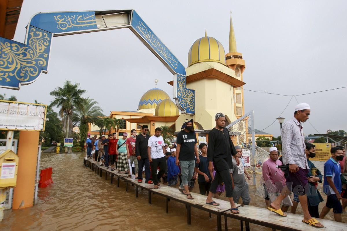 Jemaah di Masjid As Syarif, Pekan Meru, Klang menggunakan titi yang disediakan selepas selesai menunaikan solat Jumaat berikutan banjir akibat hujan lebat pada 11 Novermber. FOTO FAIZ ANUAR