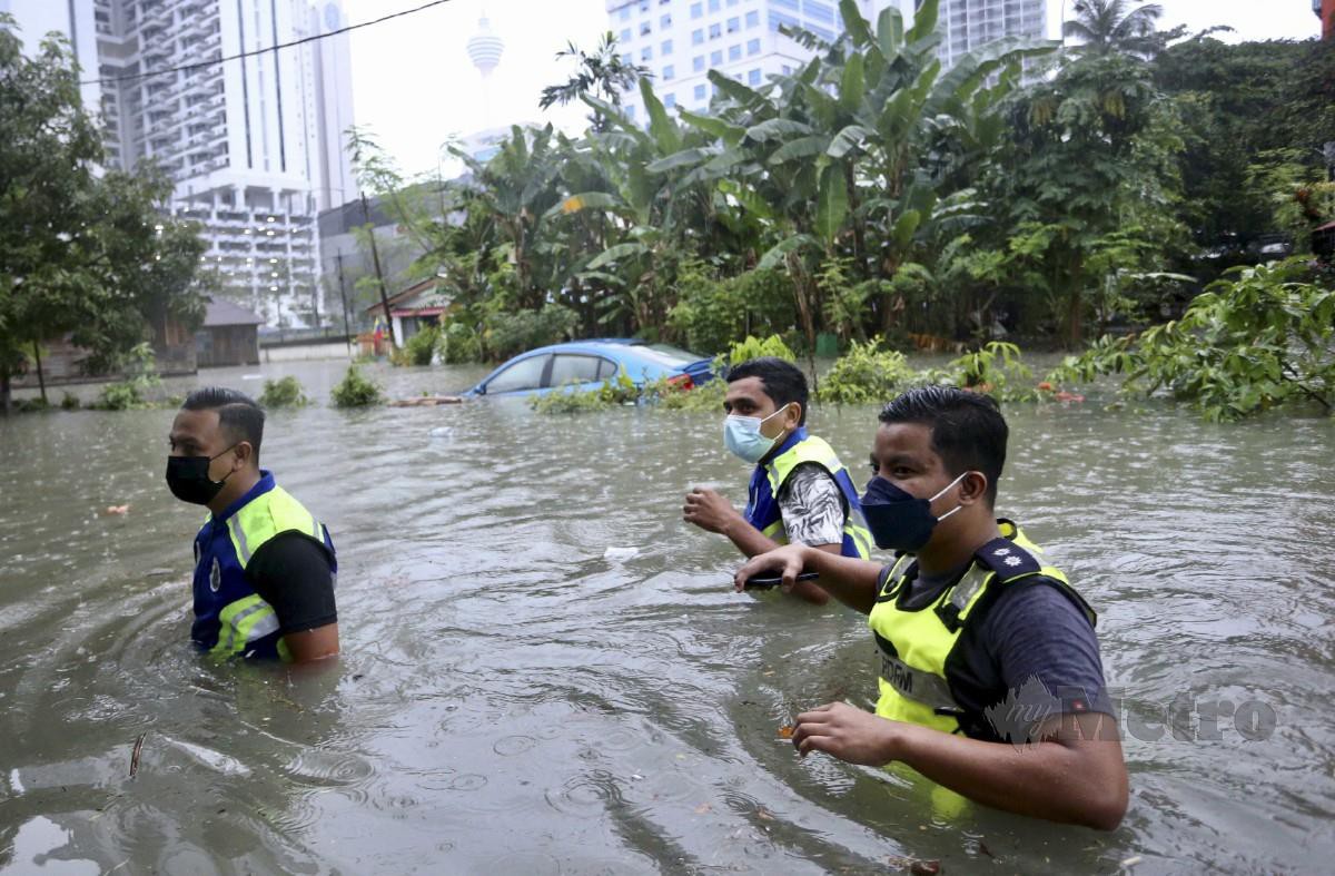 Anggota polis melakukan pemeriksaan di Kampung Periuk, Kampung Baru, pada 7 Mac selepas hujan lebat di sekitar Kuala Lumpur mengakibatkan air naik dan banjir kilat di beberapa lokasi. FOTO FATHIL ASRI
