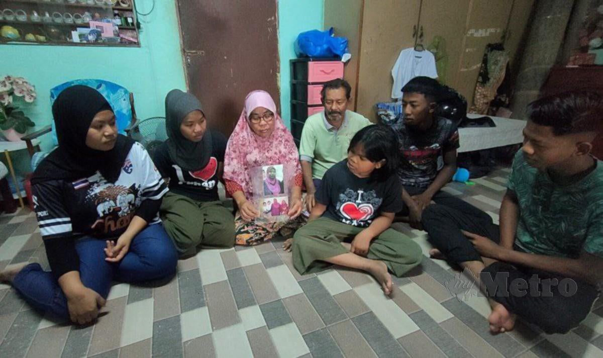 JAMARIAH (tiga kiri) bersama Khamis (empat kiri) serta lima cucunya melihat gambar arwah ibu mereka yang meninggal dunia akibat kanser perut. FOTO Zuliaty Zulkiffli