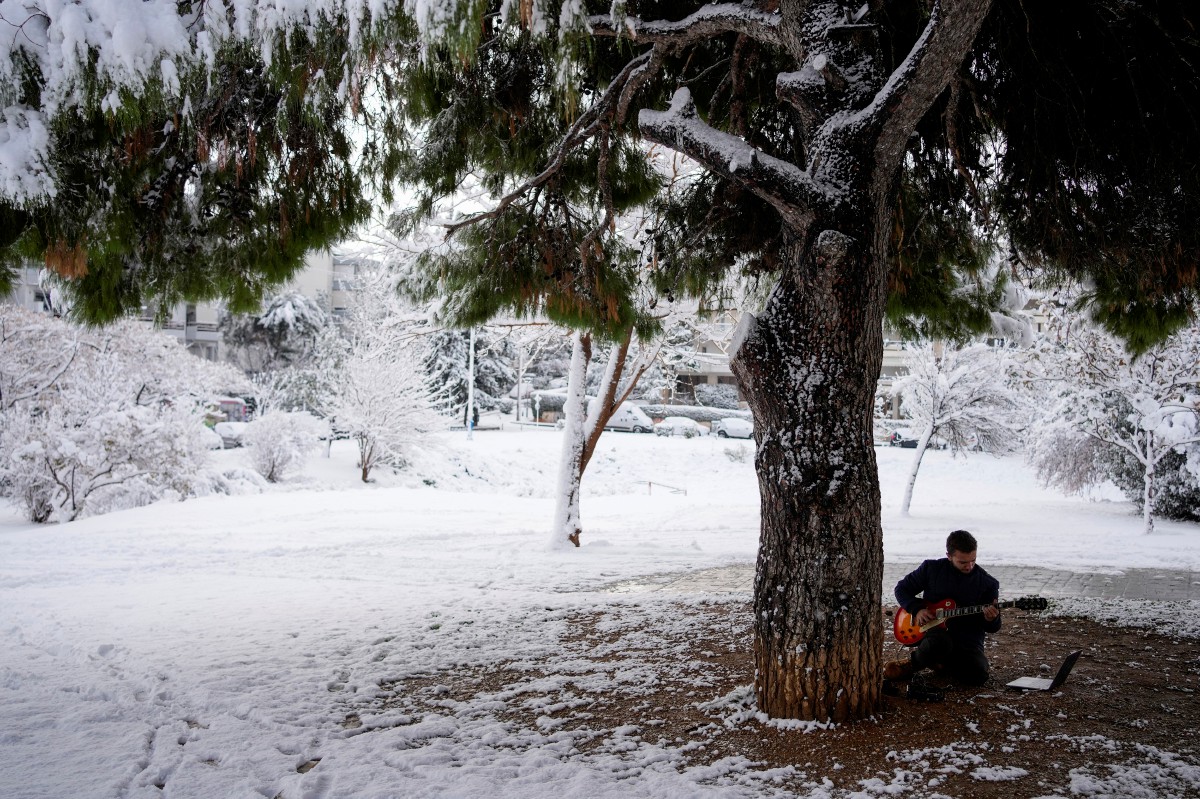 Goulielmos, 24, bermain gitar di taman di Vrilisia, Athens. FOTO AP