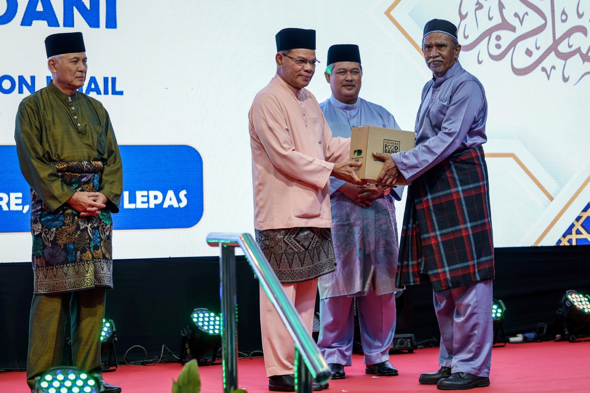 SAIFUDDIN Nasution Ismail menyampaikan sumbangan kepada penerima yang terpilih pada Majlis Penerapan Nilai-Nilai Murni dan Iftar KDN Madani hari ini. FOTO Bernama.