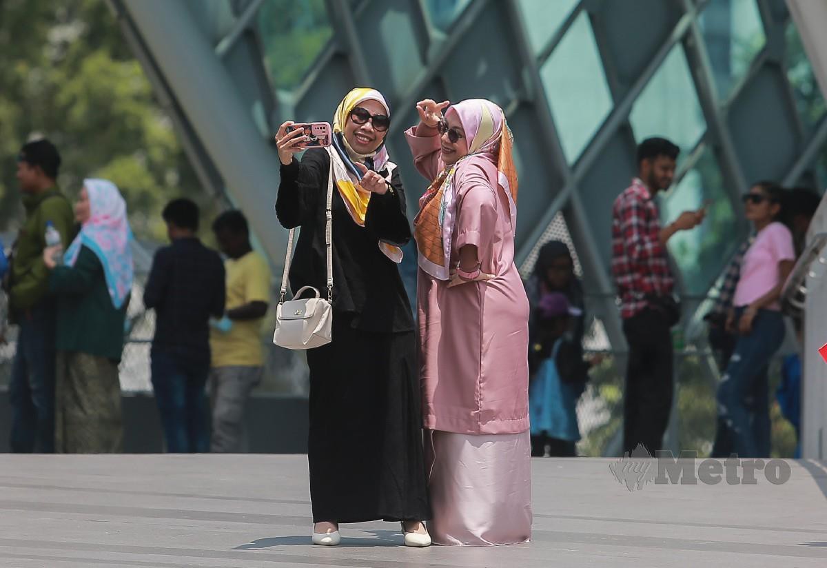 Orang ramai mengambil peluang untuk bergambar bersama kawan dan ahli keluarga di Jambatan Saloma, Kuala Lumpur. FOTO Genes Gulitah