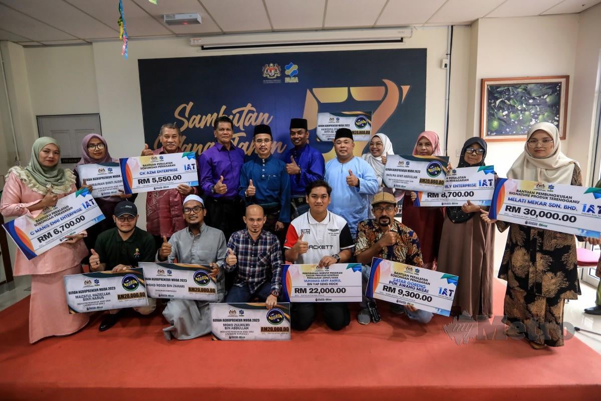 ABDUL Rashid (berdiri, lima kiri) bersama penerima bantuan usahawan  pada Majlis Penyerahan Bantuan Peralatan Sokongan Pemasaran Usahawan Negeri Terengganu. FOTO Ghazali Kori