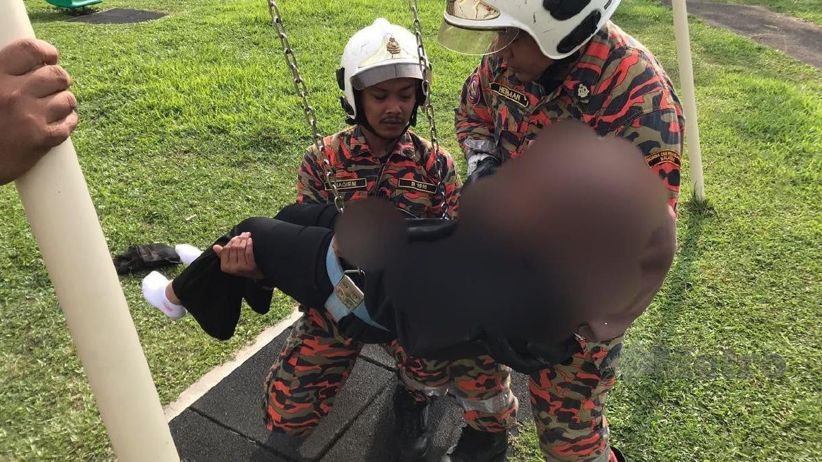 ANGGOTA bomba  mengeluarkan remaja yang tersangkut pada buaian. FOTO ihsan Bomba