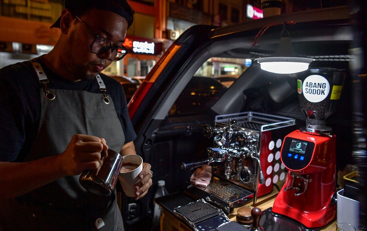 MOHAMAD Hazreel yang mengusahakan ‘kedai kopi’ menggunakan bahagian but kenderaan milik keluarganya. FOTO Bernama