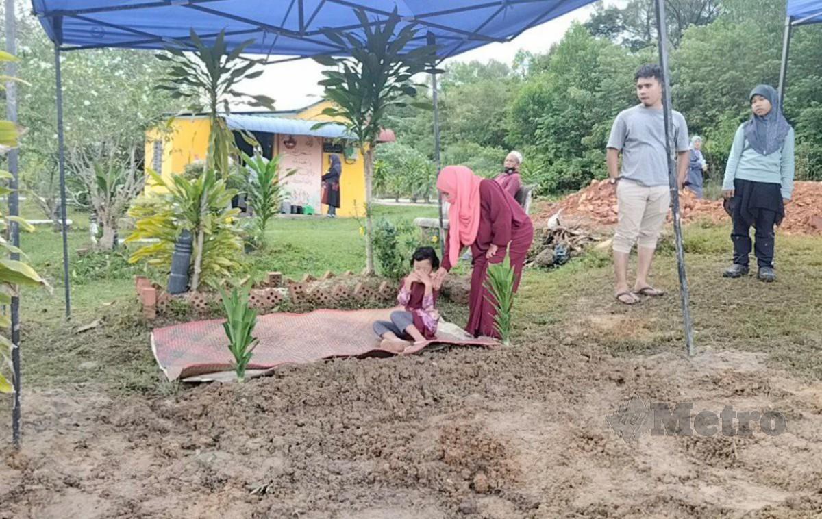 NUR Liyana menemani anak saudaranya, Mawardah iaitu anak sulung Hazlami di pusara bapanya selepas selesai pengebumian di Tanah Perkuburan Islam Kampung Bukit. FOTO Zuliaty Zulkiffli
