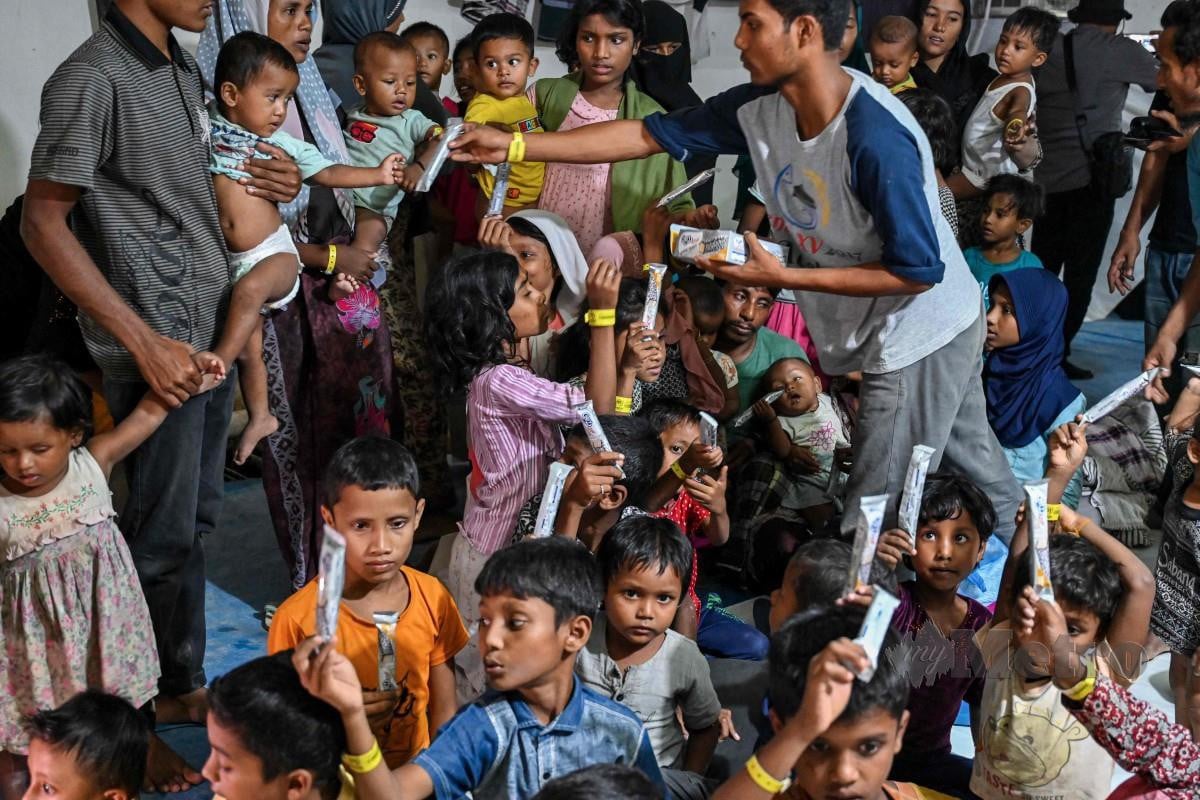KANAK-KANAK Rohingya menerima makanan daripada wakil Majlis Ulama Aceh (MPU) di penempatan sementara Banda Aceh. FOTO AFP