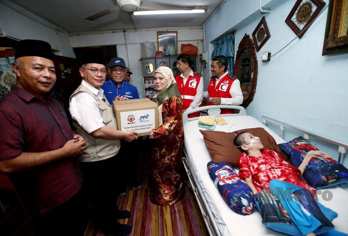 MOHD Na'im menyampaikan sumbangan kepada Jamsiah Mohd Said yang anaknya, Muhammad Aisamuddin Mohd Ishak, 24 mengalami penyakit celebral palsy. FOTO Eizairi Shamsudin