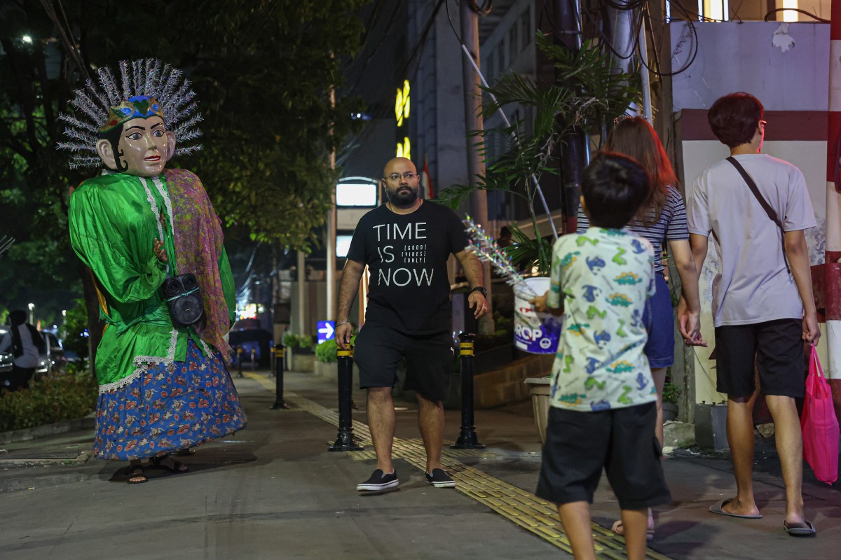 PENGHIBUR jalanan mengenakan kostum gergasi yang dikenali sebagai Ondel-Ondel  menghiburkan orang ramai dengan tarian mengikut alunan muzik yang dimainkan menerusi pembesar suara bersaiz mini di Jakarta. FOTO Bernama
