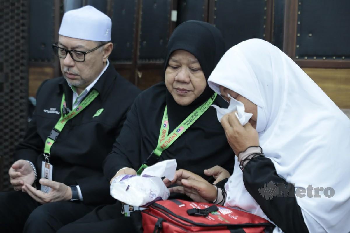 ISTERI Allahyarham (kanan) sedang ditenangkan oleh isteri Ketua Rombongan Haji Malaysia, Datin Seri Junaida Ahmad.