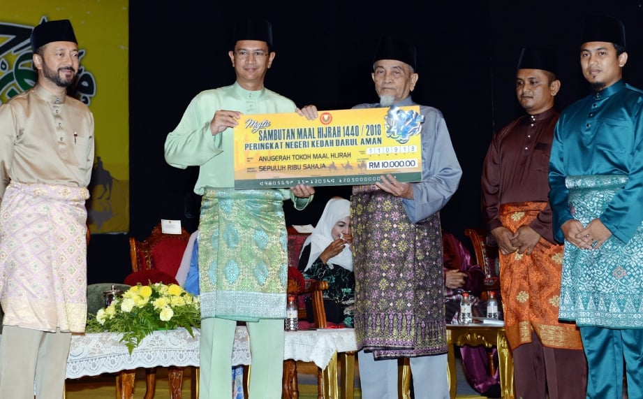 TENGKU Sarafudin Badlishah menyampaikan replika cek kepada Tokoh Maal Hijrah,  Zainal Abidin Sudin sambil disaksikan oleh Mukhriz (kiri). FOTO Amran Hamid