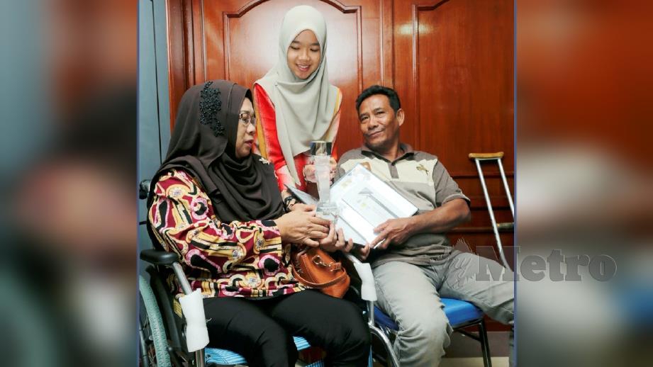 Nuraqilah Atikah menunjukkan sijil penghargaan kepada ibu bapanya selepas menerima BKMB. FOTO Zulkepli Osman