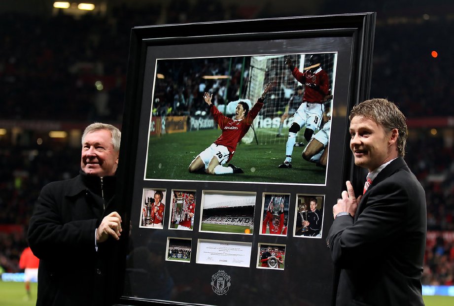 SOLSKJAER (kanan) menerima gambar dia meraikan jaringan final Liga Juara-Juara 1999 daripada Alex Ferguson. — FOTO Agensi