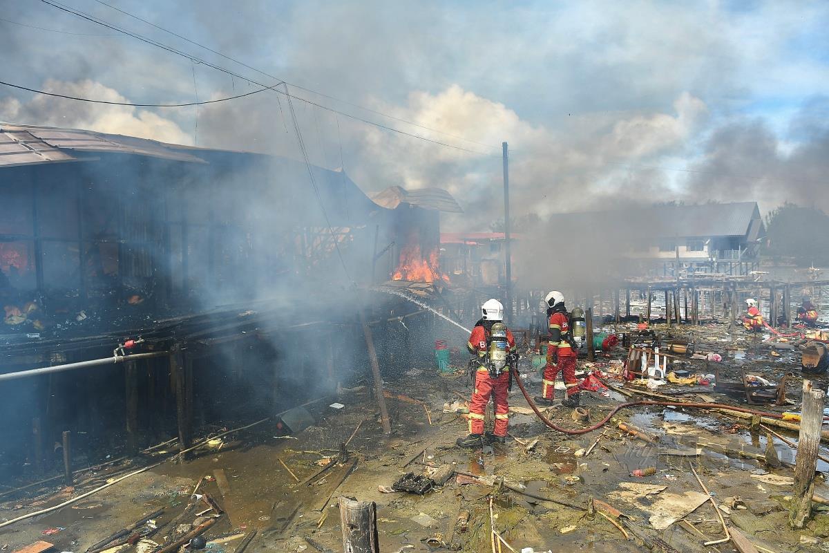 ANGGOTA bomba berusaha memadamkan kebakaran yang memusnahkan beberapa rumah di perkampungan atas air di Kampung Tanjung Aru Lama hari ini.  FOTO Mohd Adam Arinin