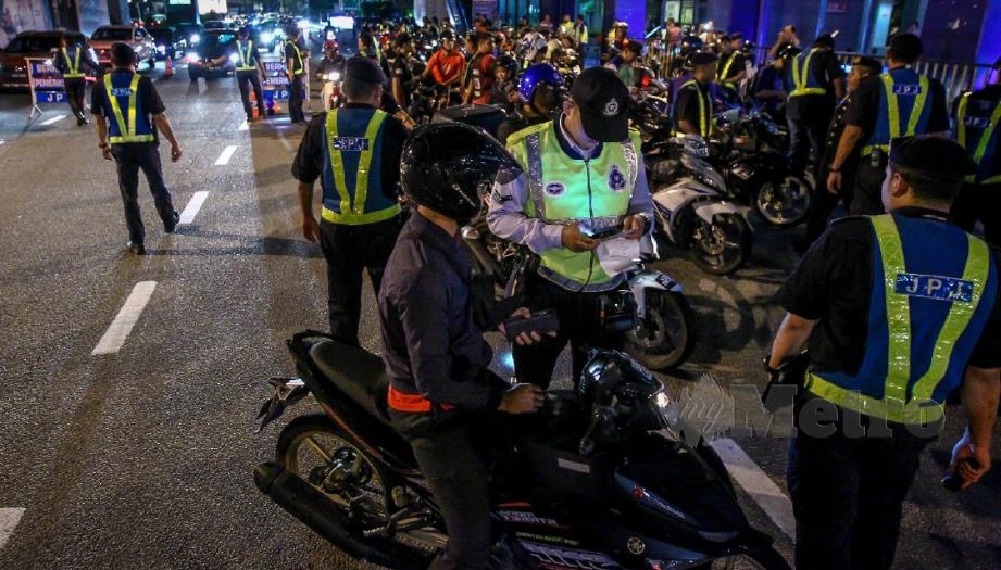 ANGGOTA JPJ dan polis trafik memeriksa penunggang motosikal dalam Operasi Bersepadu JPJ Kuala Lumpur di Jalan Bangsar, Kuala Lumpur, malam tadi. FOTO ASYRAF HAMZAH