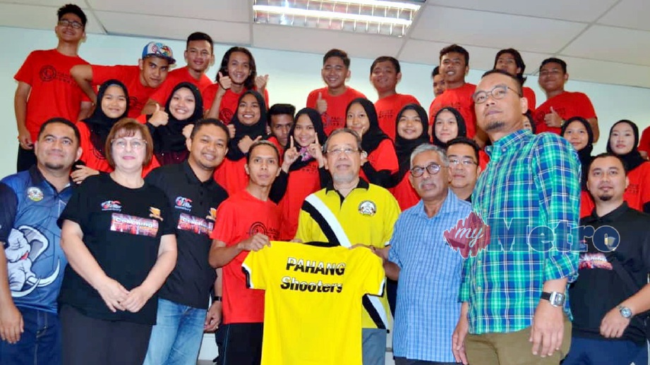 Abd Khadir (baju kuning) menyerahkan baju T kepada wakil atlet penembak Pahang. FOTO ASROL AWANG