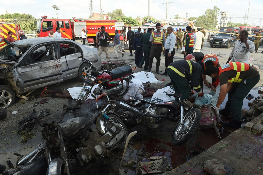 Pasukan perubatan mengangkat mayat mangsa ketika polis memeriksa kawasan letupan. - Foto AFP