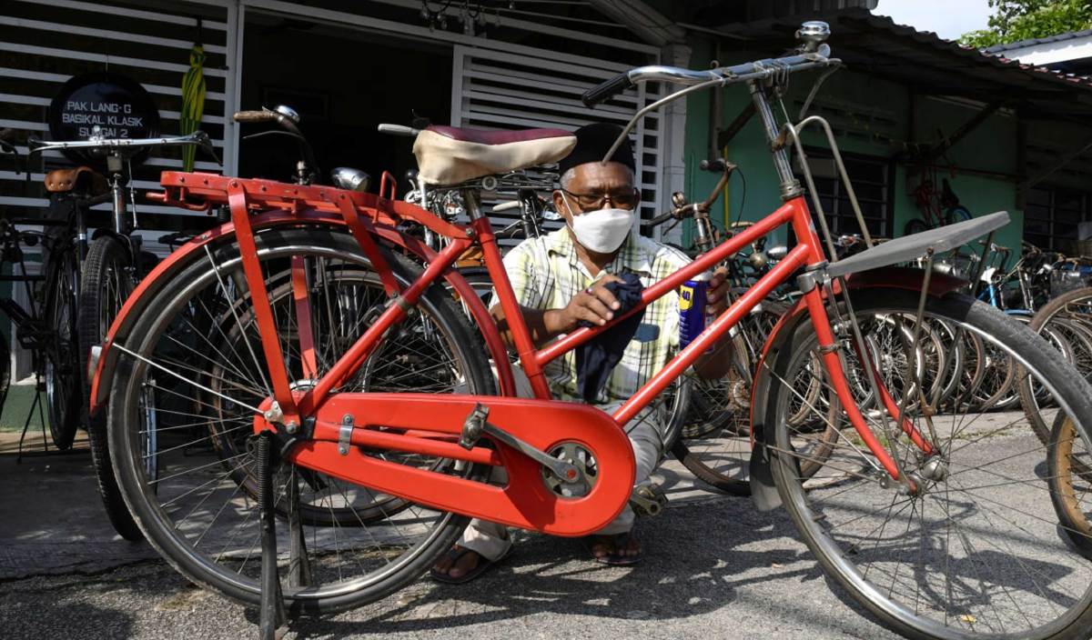 AHMAD Fauzi membersihkan basikal yang digunakan oleh posmen Jepun di kediamannya di Sungai Dua. FOTO BERNAMA