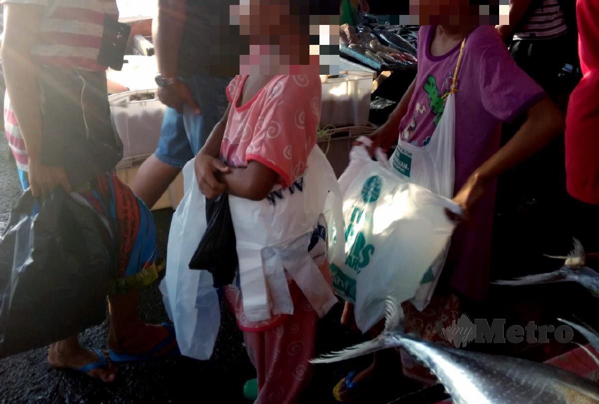 KANAK-kanak Palauh menjual beg plastik kepada pengunjung yang membeli barangan keperluan harian di sekitar Kota Kinabalu. FOTO arkib NSTP
