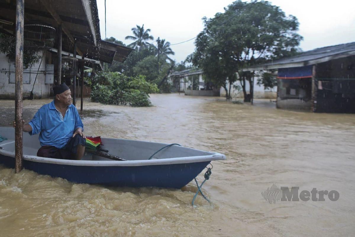 PENDUDUK, Razan Ahmad, 63, menaiki sampan untuk meninjau keadaan rumahnya yang dinaiki air susulan hujan berterusan sejak petang semalam di Kampung Padang Kubu. FOTO Ghazali Kori