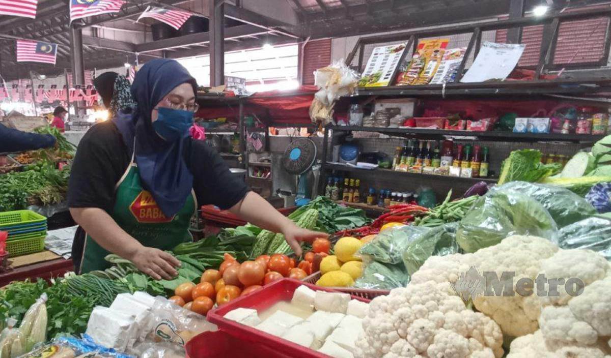 NORHAZANA menyusun sayuran digerainya di Pasar Chabang Tiga. FOTO Zaid Salim