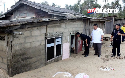 MAZLAN (kiri) meninjau rumah yang roboh akibat ombak besar di Pantai Pulau Kundur, Kuala Besar.