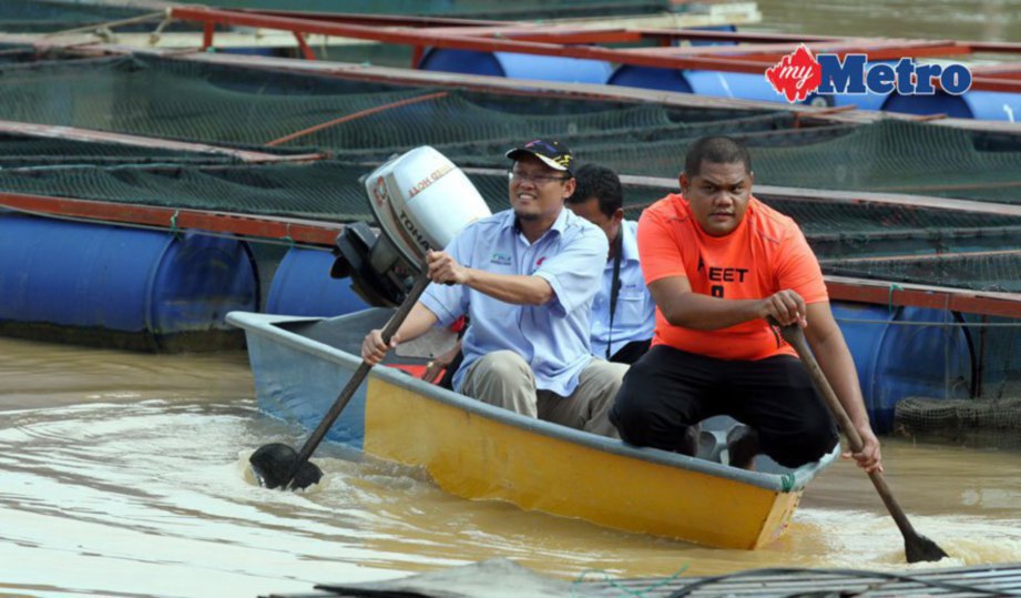 ADNAN (kiri) meninjau keadaan sangkar ikan yang dilanda banjir di Sungai Pahang.  FOTO Mohd Rafi Mamat 