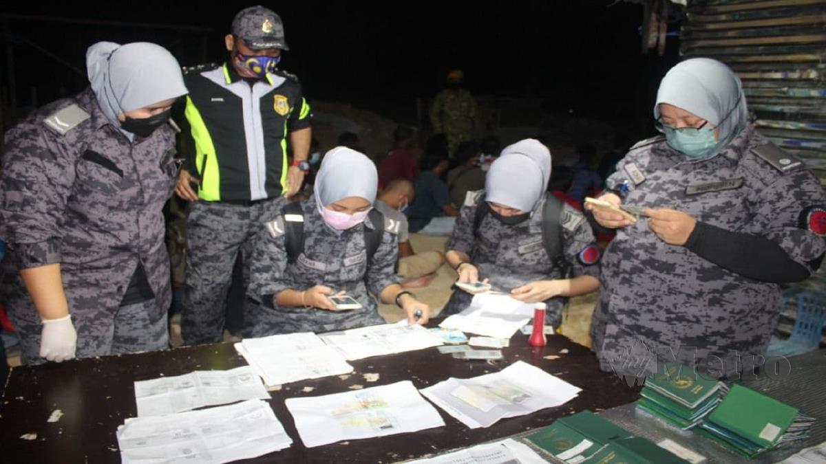 PENGUAT kuasa memeriksa dokumen warga asing dalam serbuan di sebuah tapak pembinaan di Tanjung Minyak. FOTO Ihsan JIM