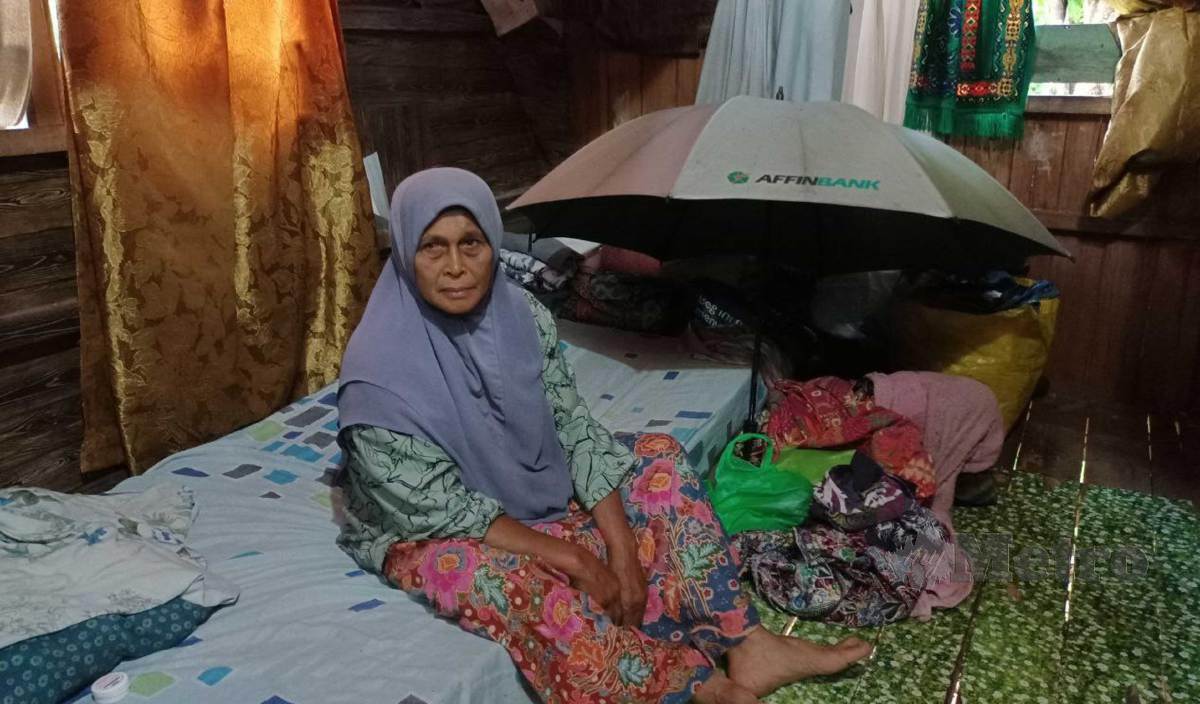 MAZNAH menunjukkan payung yang digunakan ketika berlindung dari hujan disebabkan bumbung rumah yang bocor. FOTO Siti Rohana Idris