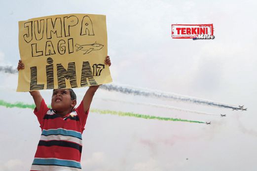 SUHAL Khan, 8, memegang poster yang bertulis `JUMPA LAGI LIMA17' sambil menyaksikan persembahan udara skuad Al-Fursan dari UAE pada hari terakhir LIMA`15. FOTO Ghazali Kori
