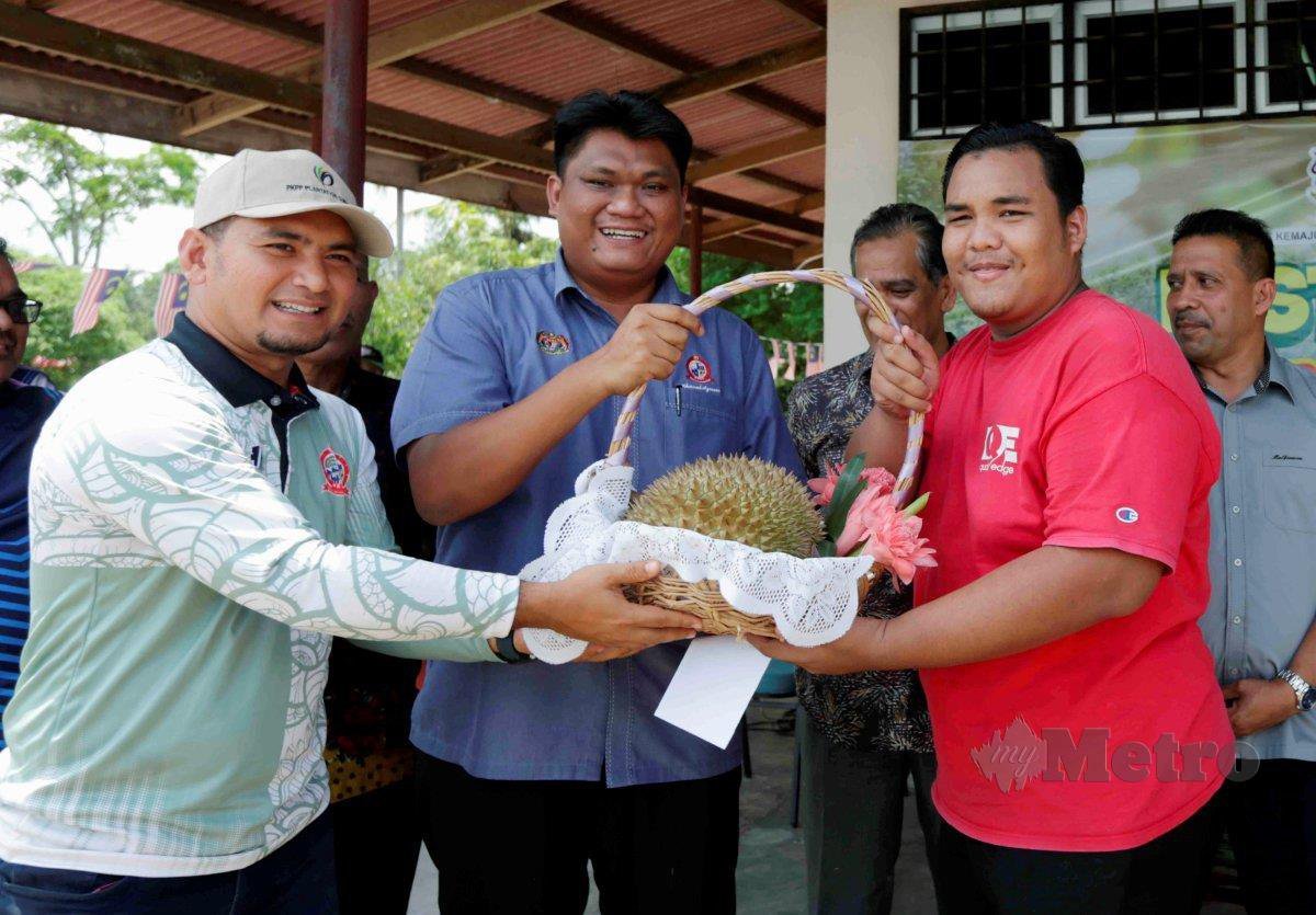 KHAIRUL Azmeer (dua dari kiri) menyampaikan hadiah kepada pemenang teka berat buah durian, Eikmal Hazim Othman, 22, ketika Program Lawatan Penanda Aras PPRT Daerah Padang Terap dan PROSPEK Pedu.
