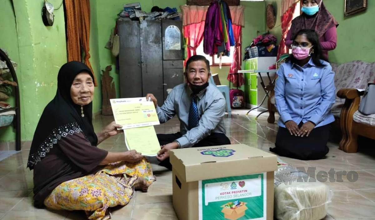 HASMAH (kiri) menerima replika cek RM 2,000 bersama barang keperluan daripada Pengarah Pertubuhan Keselamatan Sosial (PERKESO) Zainol Abu di rumahnya di Kampung Jerang Belanga, Bagan Terap. FOTO Amirul Aiman Hamsuddin