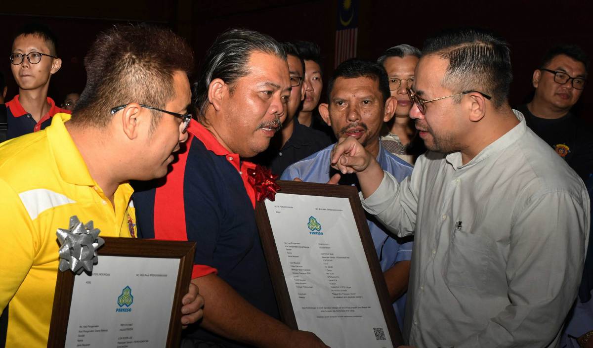 STEVEN Sim Chee Keong ( kanan) beramah mesra dengan anggota Bomba Sukarela selepas menyampaikan sijil caruman Skim Keselamatan Sosial Pekerjaan Sendiri (SKSPS) di Wisma Perkeso Seberang Jaya. FOTO BERNAMA