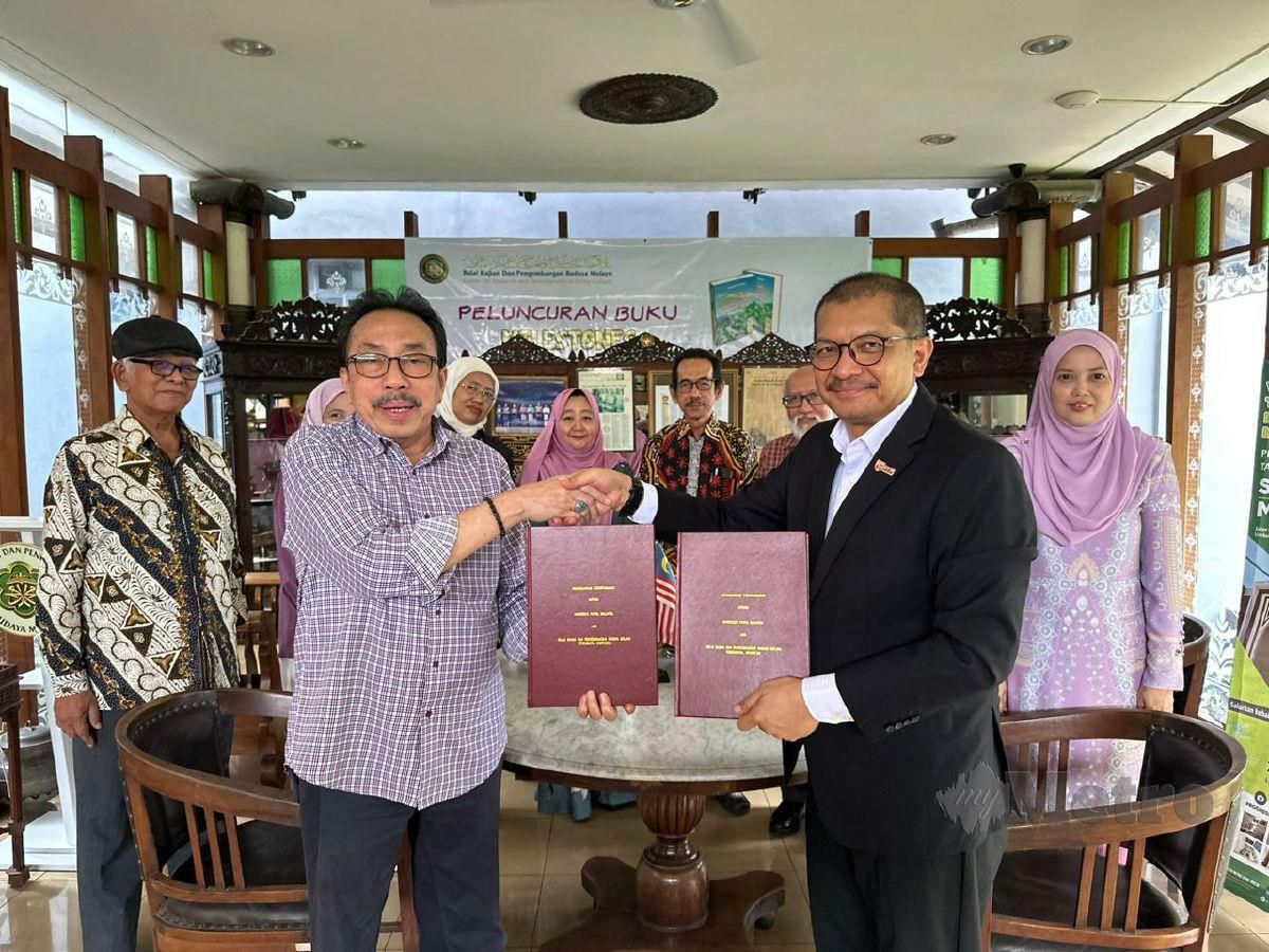MOHD Roslan (kanan) bersalaman dengan H Mahyudin Al Mudra selepas majlis menandatangani MoU kerjasama memartabatkan bahasa Melayu di rantau antarabangsa. FOTO ihsan UPM 