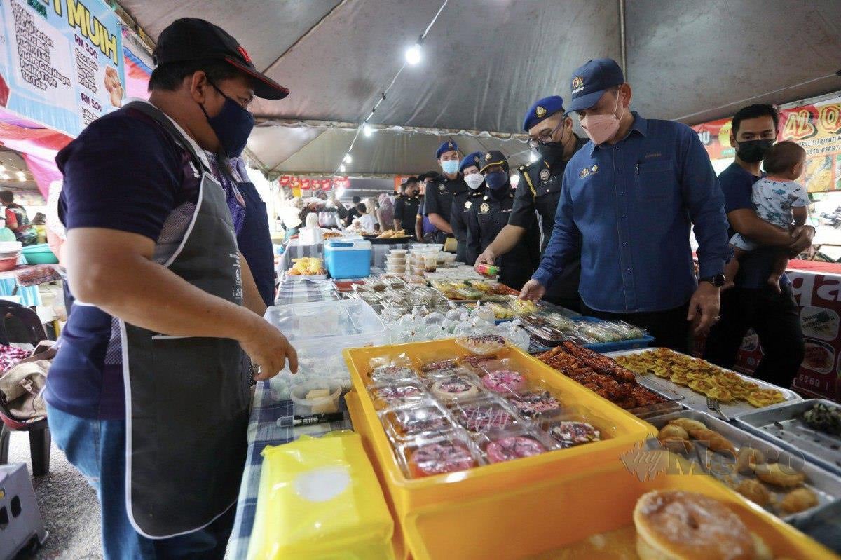 SAHARUDDIN meninjau harga makanan peniaga bazar semasa Op Pantau di Bazar Ramadan Batu Burok. FOTO Ghazali Kori