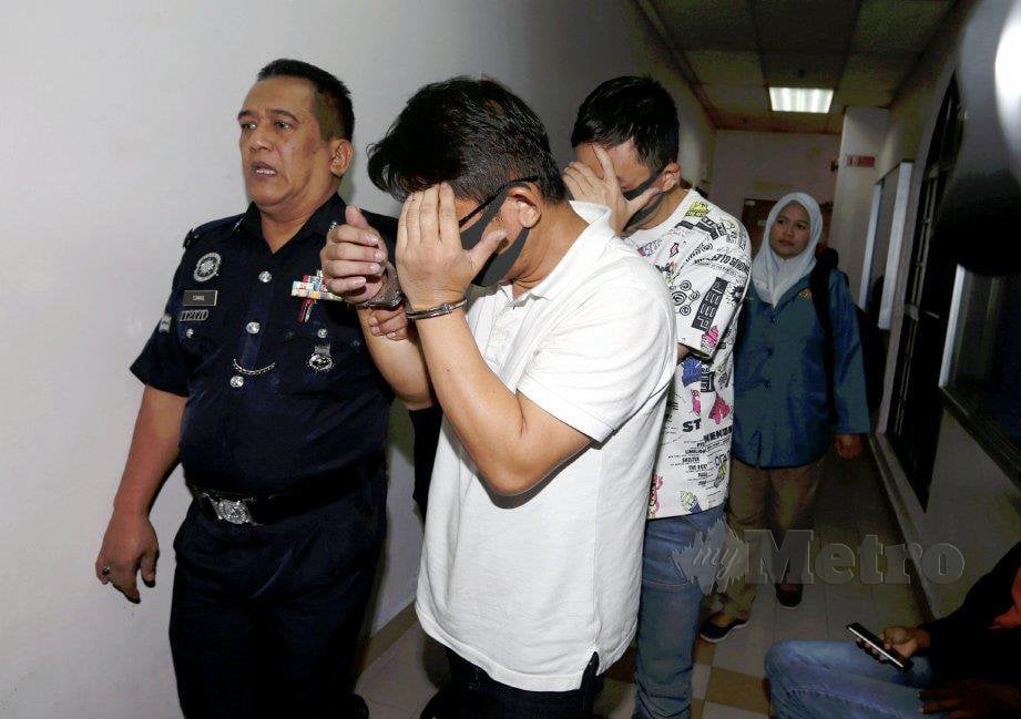 Yap (dua dari kiri) dan Wang diiringi polis ketika dihadapkan ke mahkamah bagi menghadapi tuduhan kes pembuangan sisa toksik ke Sungai Kim Kim di Mahkamah Sesyen Johor Bahru. FOTO Hairul Anuar Rahim 