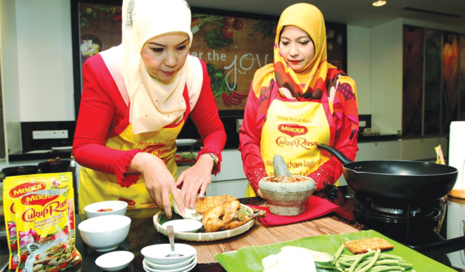 SHEILA (kiri) menunjukkan kemahirannya memasak nasi ayam penyet.