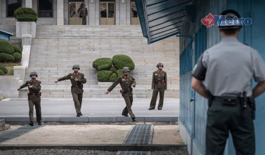 ASKAR Korea Selatan (kanan) berdiri menghadap askar Korea Utara yang berjalan di garisan sempadan yang memisahkan kedua-dua negara di kampung Panmunjom. FOTO AFP