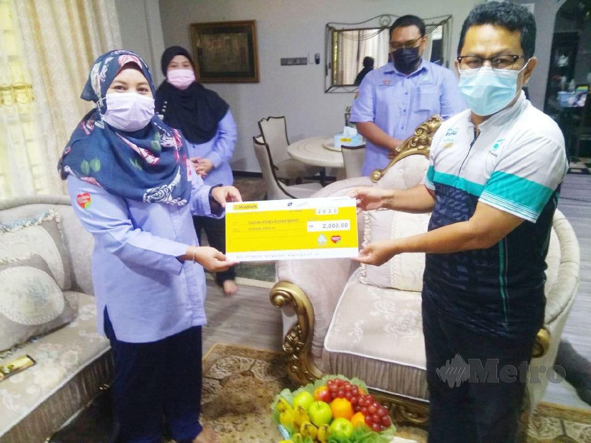 NOR Afizah menyerahkan sumbangan faedah pengurusan mayat kepada Mohd Fadzli. FOTO Rosli Ilham