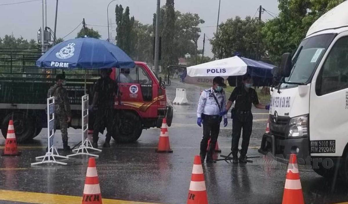 WALAUPUN hujan, polis dan anggota tentera masih tetap meneruskan tugas mereka di SJR Kuala Perlis bagi mengawal kenderaan keluar masuk ke Kuala Perlis selepas kawasan itu mencatatkan peningkatan jumlah jangkitan Covid-19 di Perlis. FOTO Aizat Sharif