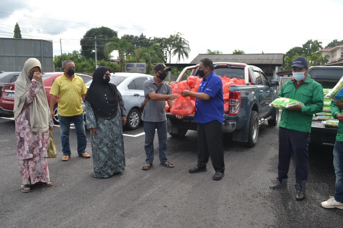 Nor Azman Hassan (tengah) menyerahkan bahan makanan disumbangkan Greenviro Solution Sdn Bhd kepada petani di JAPERUN Pantai Kundor, Tanjung Kling. Foto HASSAN OMAR