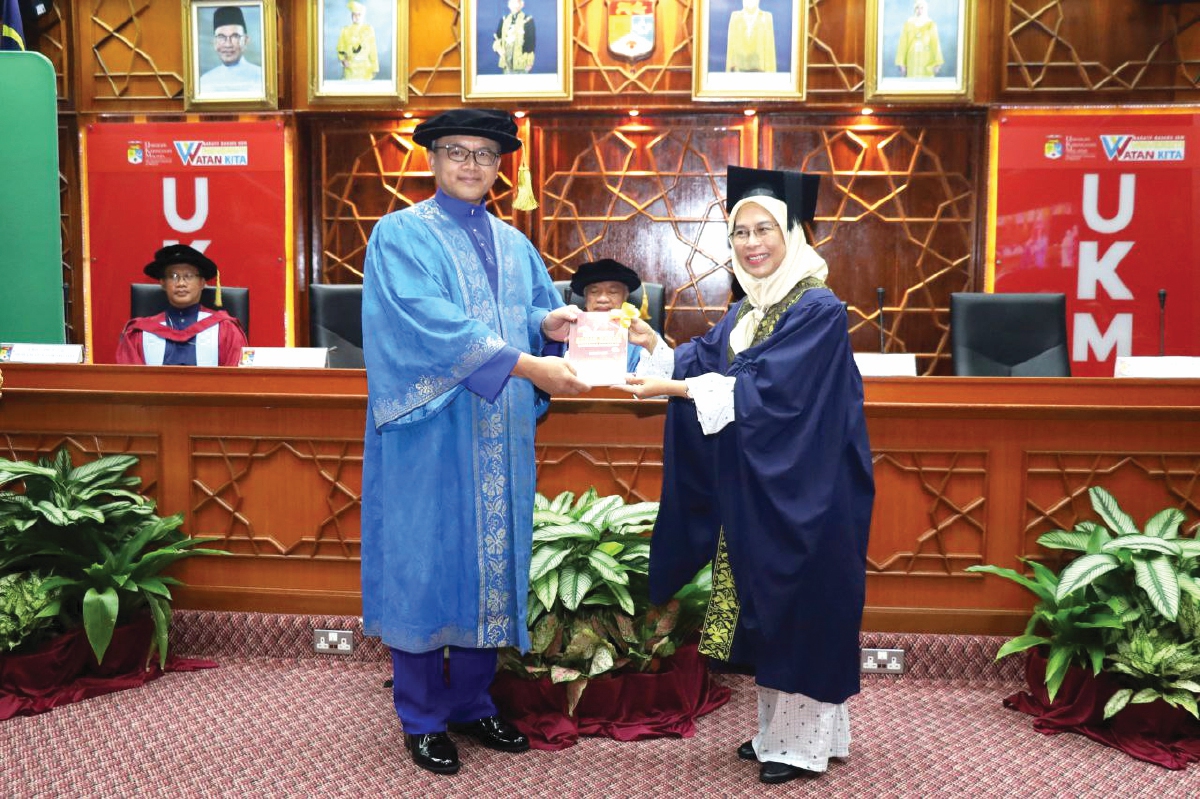 MENYAMPAIKAN buku kepada Dr Mohd Ekhwan pada majlis Syarahan Perdana Profesor di UKM, Bangi, baru-baru ini.