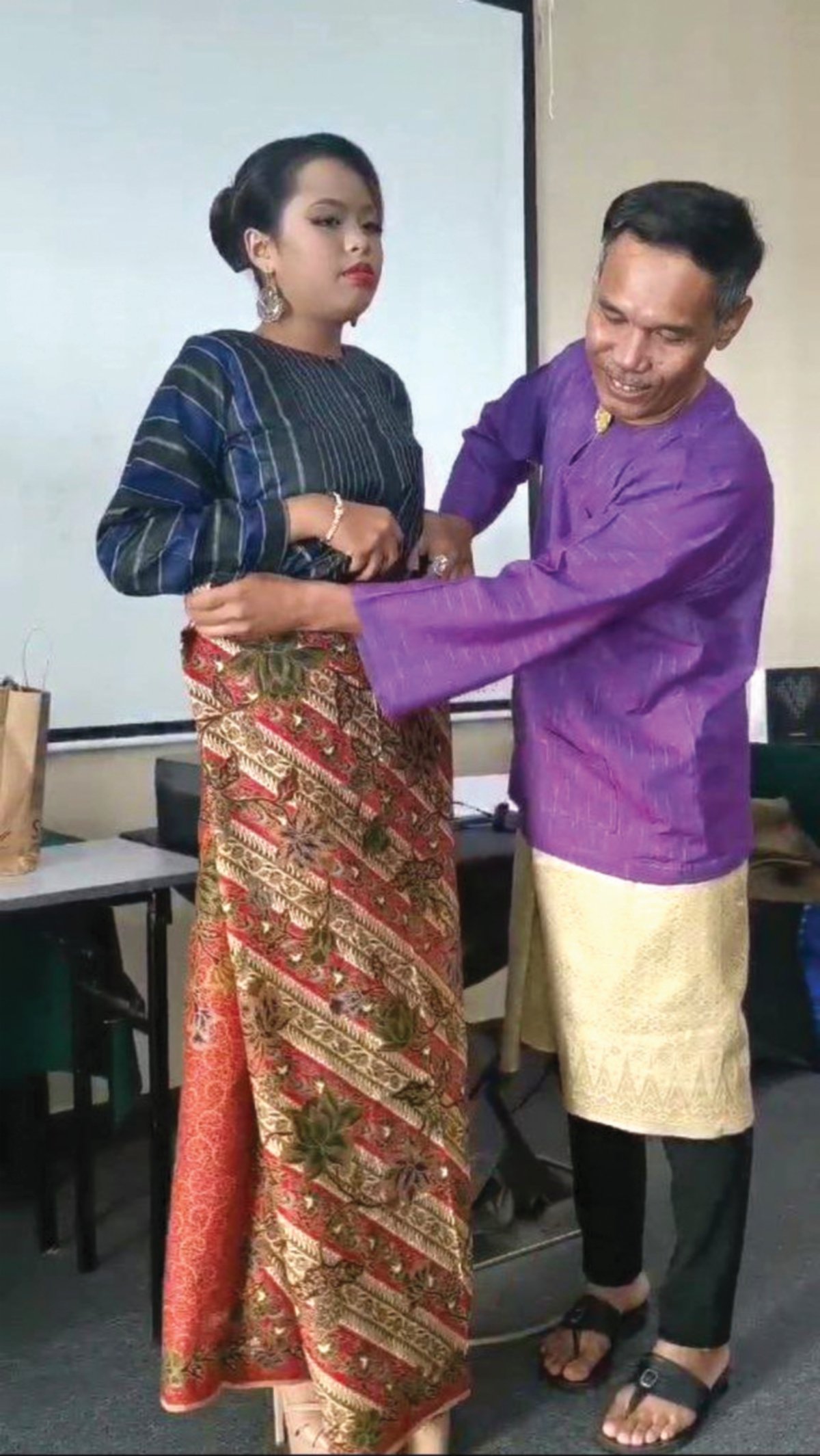 HASSAN melakukan demo kepada peserta mengenai pemakaian kain sarong.