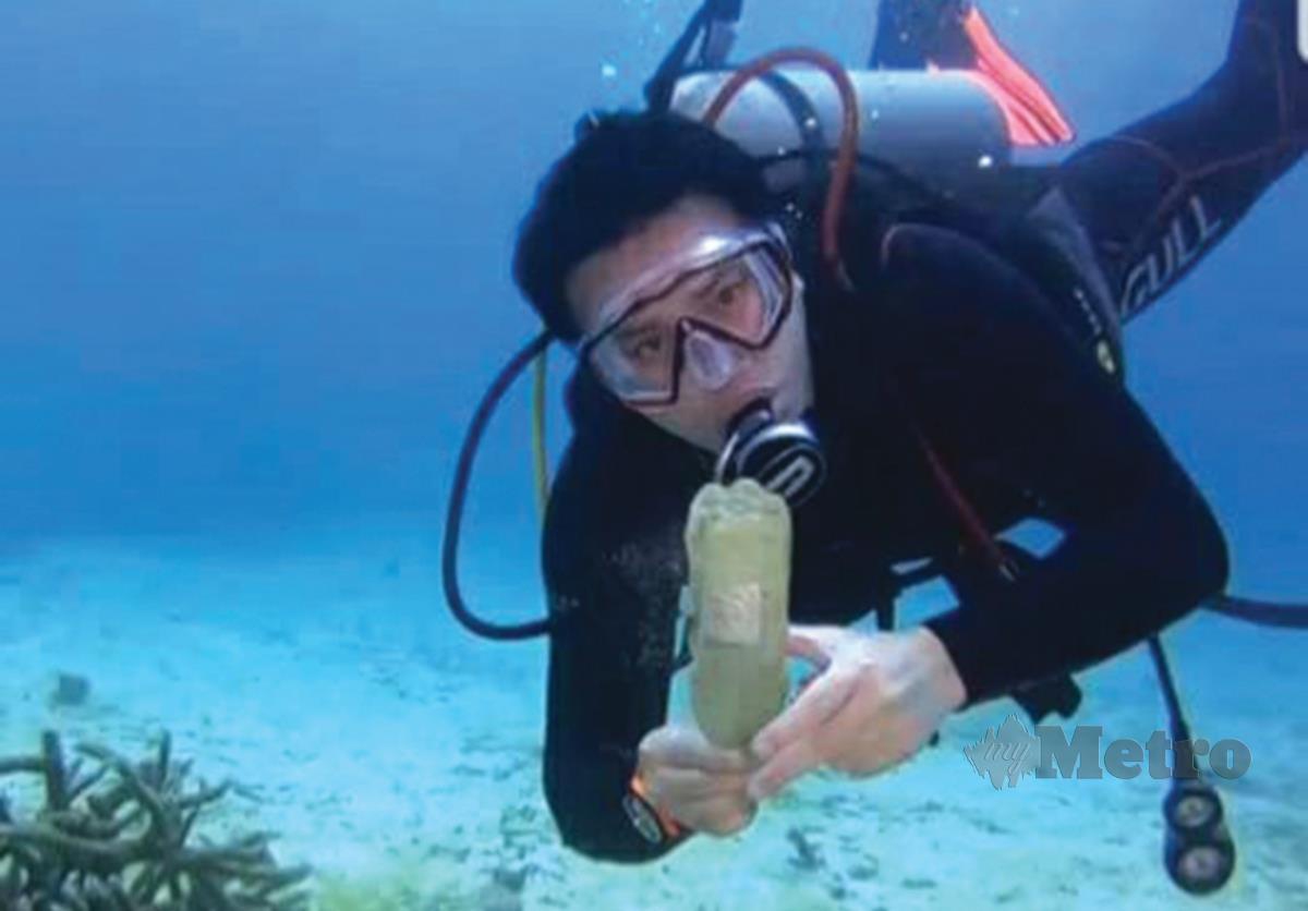 MEMEGANG botol air minuman yang dijumpai di dasar lautan.