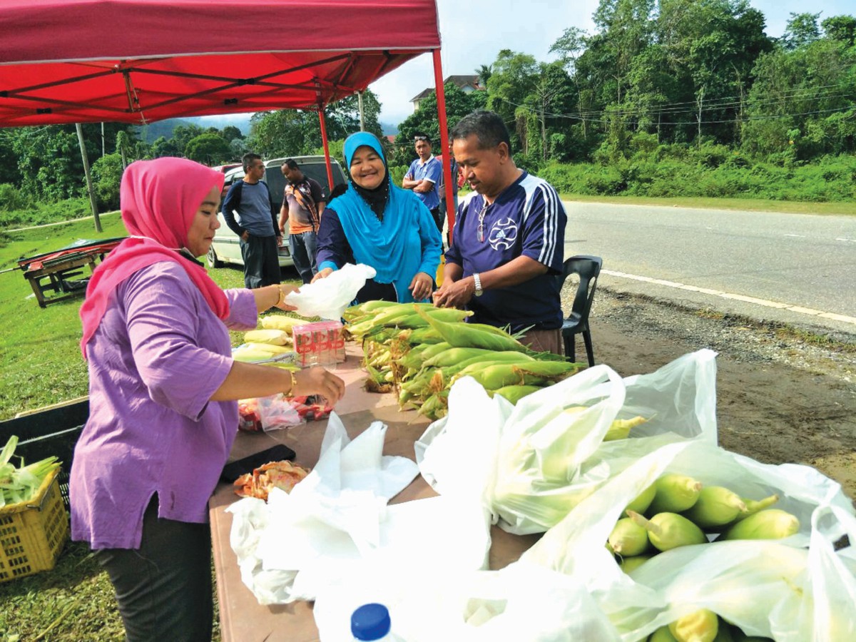 SITI Zuliha (kiri) melayan pelanggan di gerainya di tepi Jalan Jelawang-Jeli.