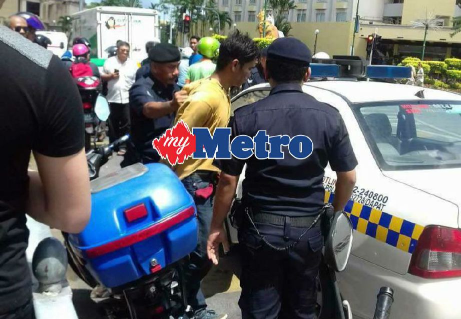 Suspek (berbaju kuning) ditahan orang awam sebelum diserahkan kepada polis.