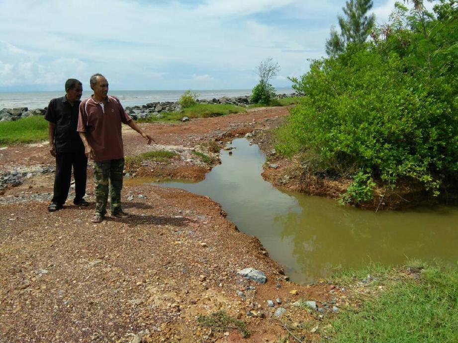 PENDUDUK Azmi Ismail, 49, (kanan) bersama Ahmad Othman, 60, menunjukkan kesan mendapan tanah akibat kejadian air pasang yang berlaku sebelum ini di Pantai Leman yang terletak kira-kira 200 meter dari rumah penduduk di Kampung Padang Garam. FOTO Zuliaty Zulkiffli