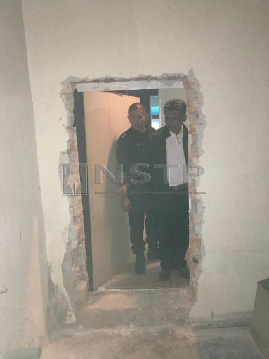 ISMADI (kanan) memeriksa lubang ditebuk pada dinding yang dijadikan sebagai pintu rahsia bagi GRO dan pekerja di sebuah pusat karaoke di Seri Kembangan, Serdang, meloloskan diri ketika serbuan pihak berkuasa. FOTO Ihsan PDRM